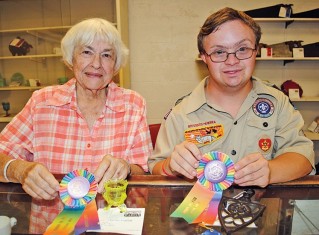 Joann Myers (left) of Kenton earned a title in the antique contest with her glass egg cup entry. Aaron Spar of Ada brought a cast iron trivet and went home with a rosette.